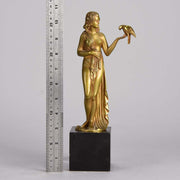 Femme avec Oiseau by Pierre Laurel an antique bronze figure of a semi clad young woman holding a bird in classic high Art Deco pose with excellent gilt patination and intricate surface detail on a square shaped black marble base 