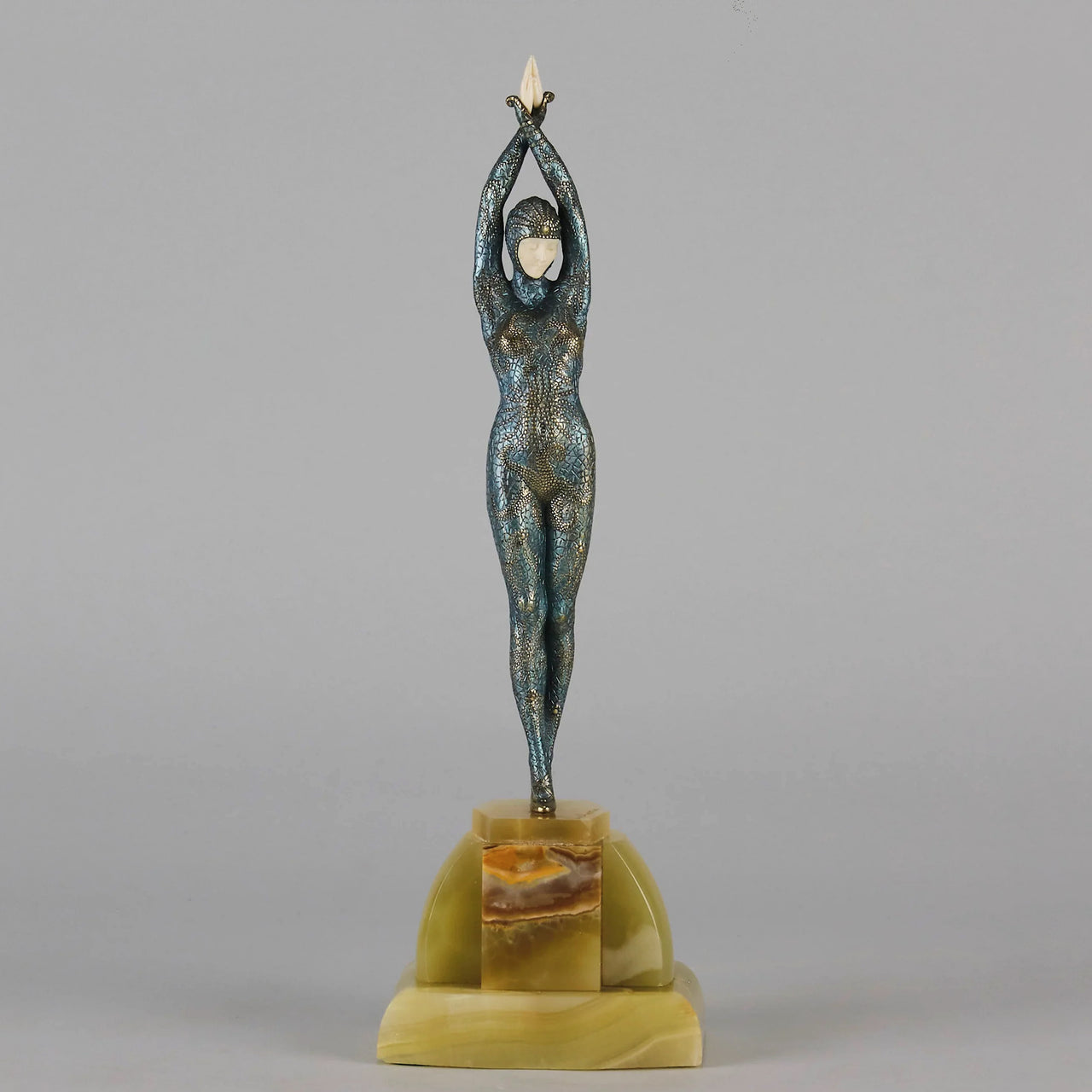  Starfish by Demetre Chiparus a  Art Deco cold painted silver and enamel bronze sculpture with ivory face and hands representing a young female Ballets Russes dancer wearing a metallic blue skin tight leotard further decorated in a bejewelled starfish pattern, modelled reaching upwards with both arms, her hands interlaced. Raised on a shaped onyx base