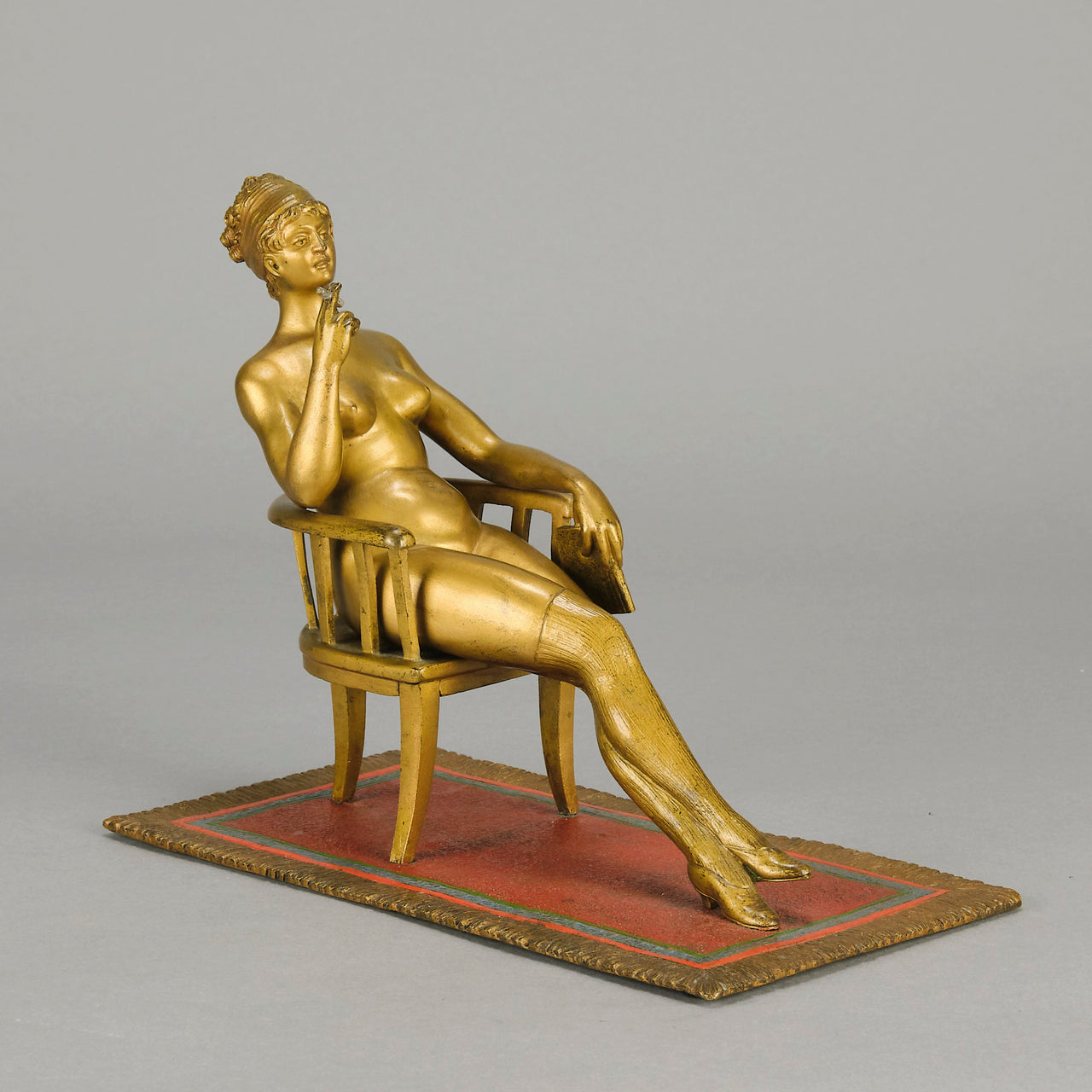 Vienna Bronze Seated Lady - an early 20th Century cold-painted Austrian bronze figure of an attractive lady seated on an arm chair wearing only a pair of stockings and heals, holding a book whilst enjoying a cigarette