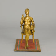 Vienna Bronze Seated Lady - an early 20th Century cold-painted Austrian bronze figure of an attractive lady seated on an arm chair wearing only a pair of stockings and heals, holding a book whilst enjoying a cigarette