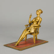 Vienna Bronze Seated Lady - an early 20th Century cold-painted Austrian bronze figure of an attractive lady seated on an arm chair wearing only a pair of stockings and heals, holding a book whilst enjoying a cigarette