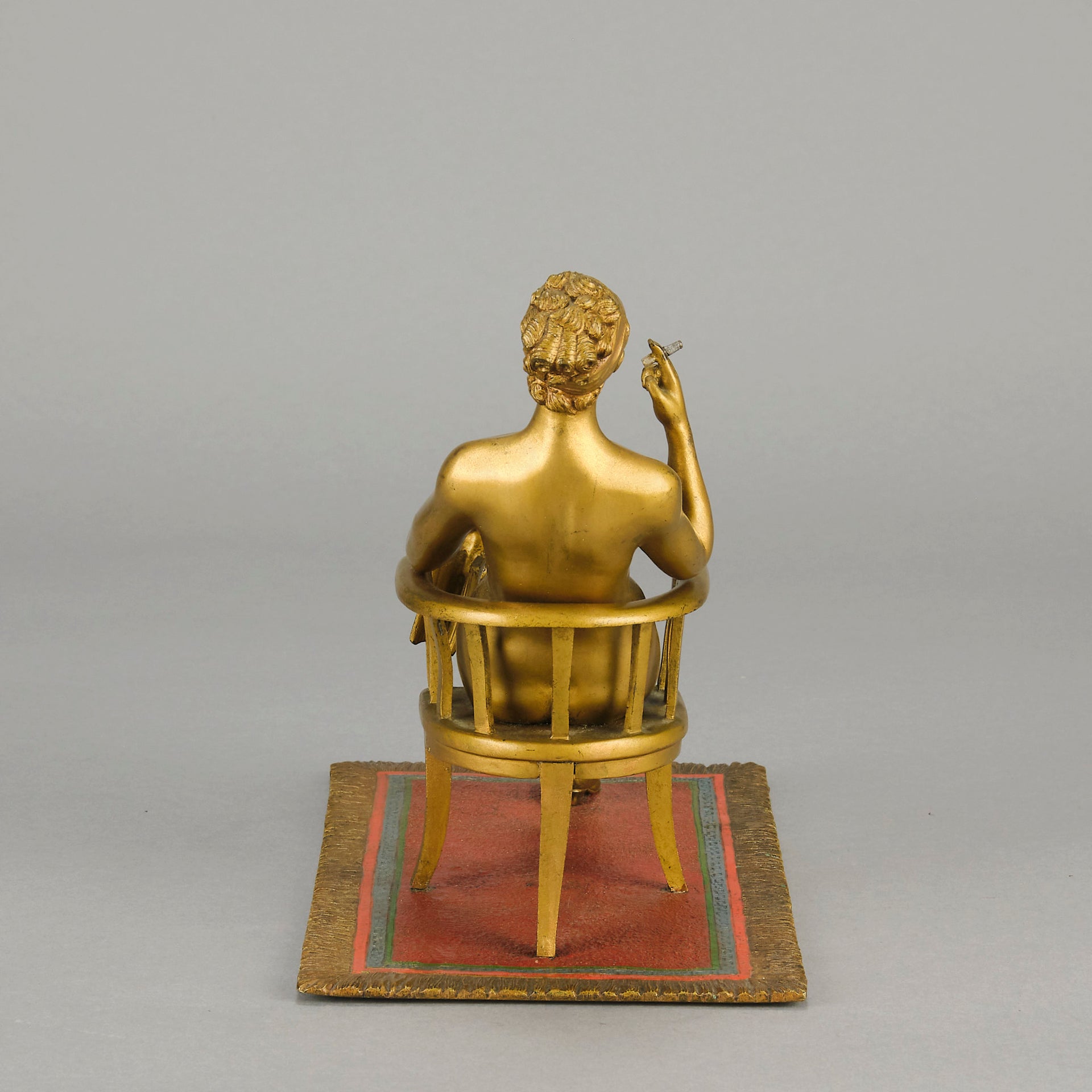 Vienna Bronze Seated Lady - an early 20th Century cold-painted Austrian bronze figure of an attractive lady seated on an arm chair wearing only a pair of stockings and heals, holding a book whilst enjoying a cigarette