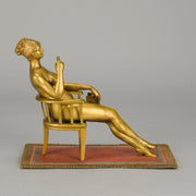Vienna Bronze Seated Lady - an early 20th Century cold-painted Austrian bronze figure of an attractive lady seated on an arm chair wearing only a pair of stockings and heals, holding a book whilst enjoying a cigarette